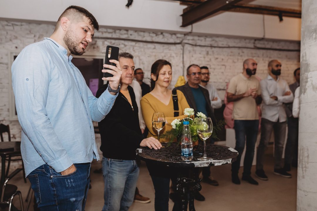 An attendee records the founder's presentation at the Bithope Foundation 10-year anniversary event in Sofia, December 2024.