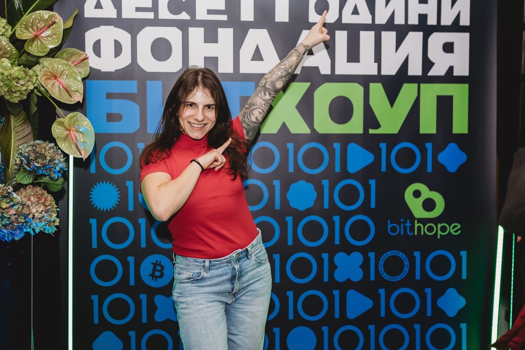 A supporter of the Bithope Foundation poses in front of the 10-year anniversary photo wall in Sofia, December 2024.