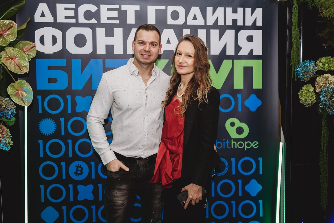 A Bulgarian crypto-community couple poses in front of the Bithope Foundation 10-year anniversary backdrop in Sofia.